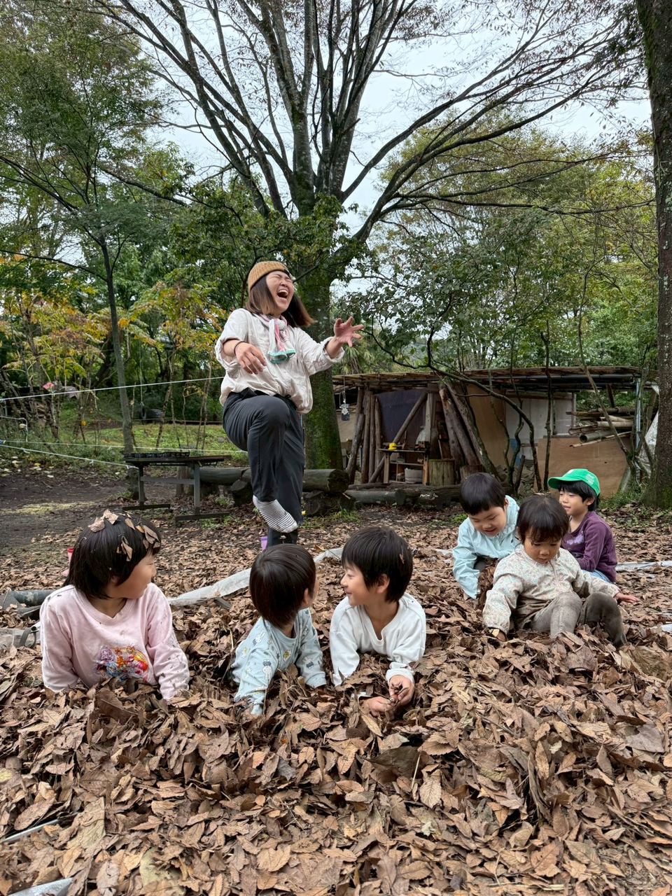 落ち葉の中で遊ぶ子どもたち