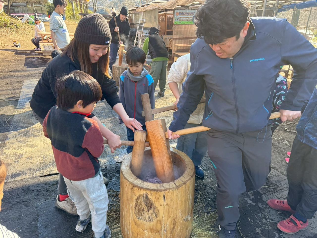 大人と子どもが一緒に杵を持ってお餅をつく様子