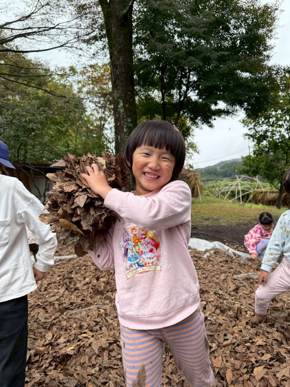 落ち葉を抱えて笑う子ども