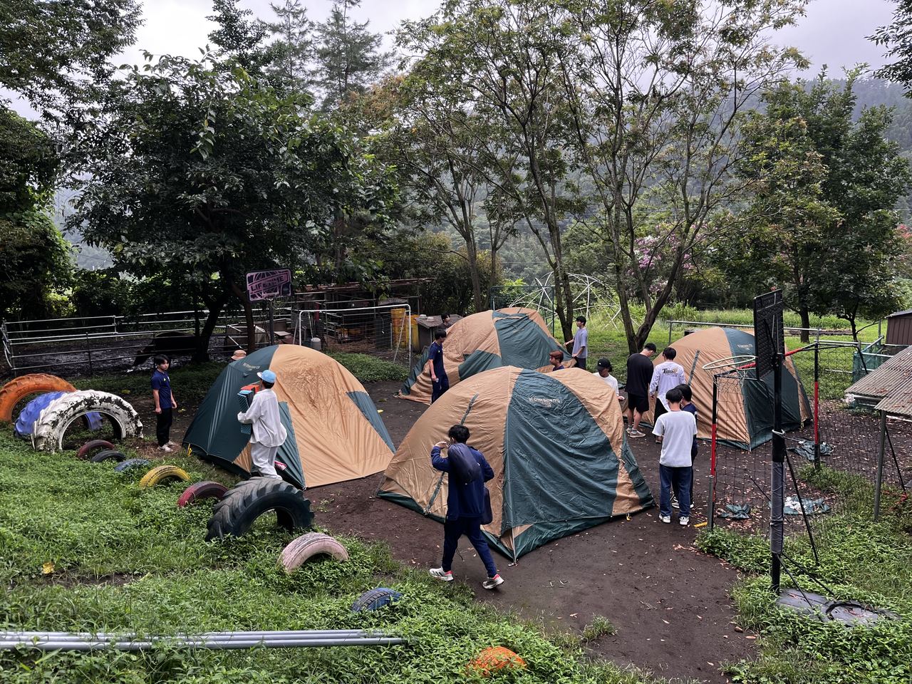 里山に並ぶテントと子どもたち